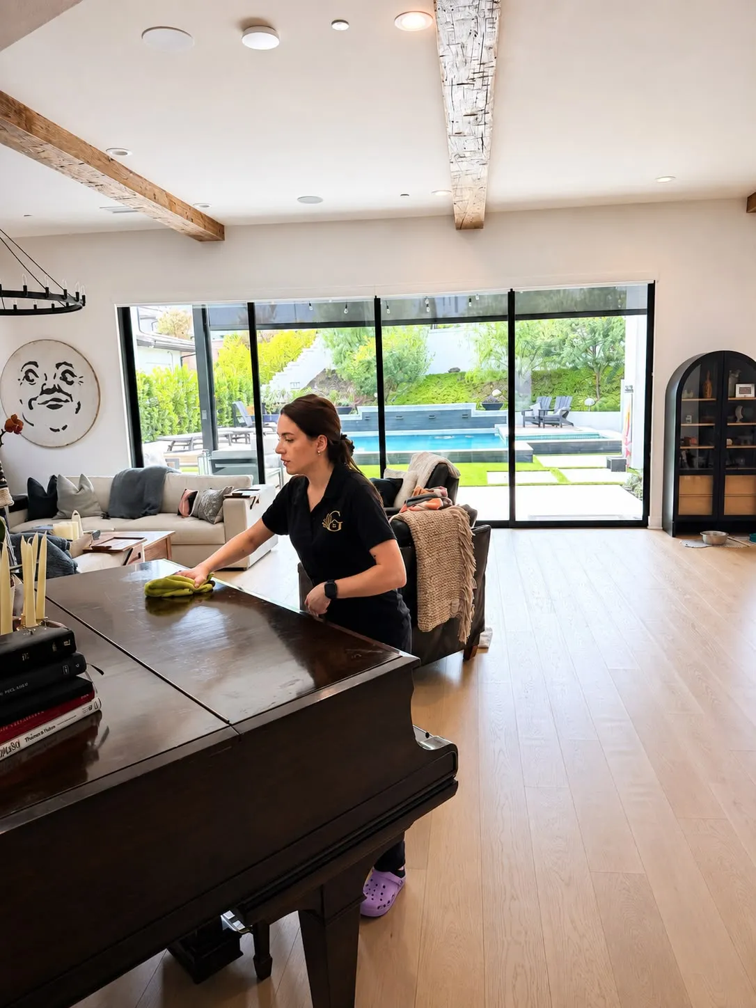 Gabby hand-polishing a grand piano in a modern Newport Coast home with a pool view