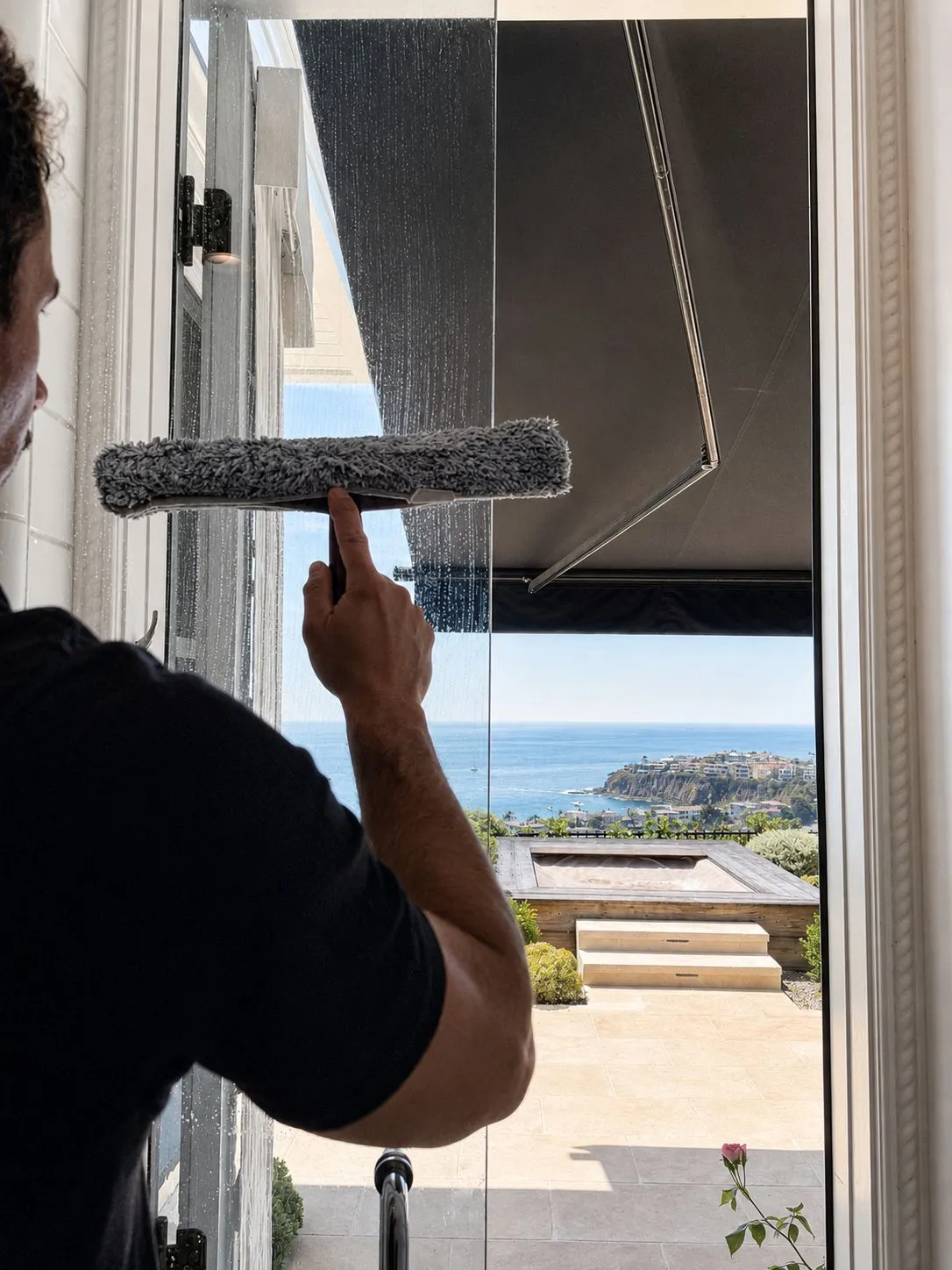 Paul squeegeeing glass doors above an ocean-view terrace in Laguna Beach